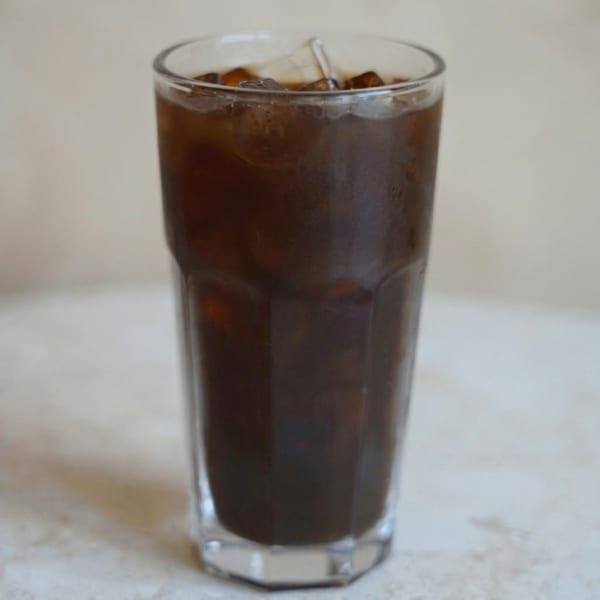 Close-up of a tall glass filled with iced coffee, showing ice cubes and condensation.