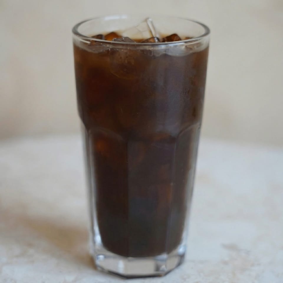 Close-up of a tall glass filled with iced coffee, showing ice cubes and condensation.